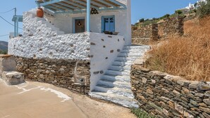 Un edificio blanco con detalles azules, escalones de piedra y un muro de piedra.