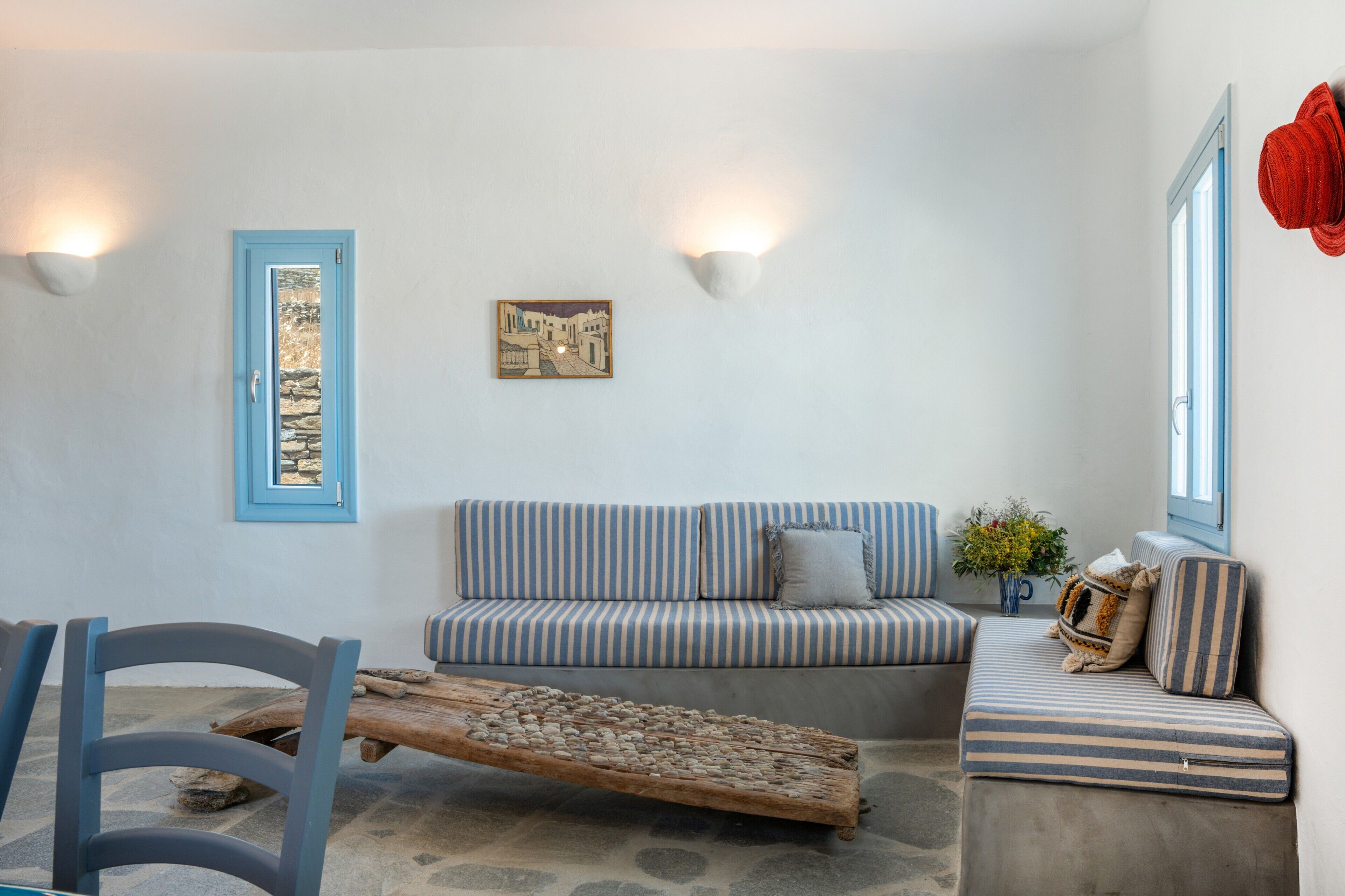 Une pièce avec un canapé à rayures, une table basse en bois, une porte à cadre bleu et des lampes fixées au mur.