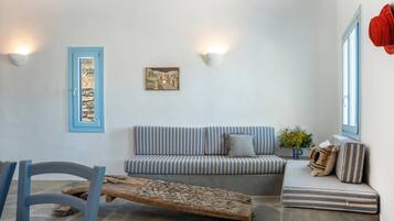 Une pièce avec un canapé à rayures, une table basse en bois, une porte à cadre bleu et des lampes fixées au mur.