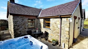 A stone house with a hot tub and outdoor seating area. - Y Dderwen, Aberaeron (Llanarth)