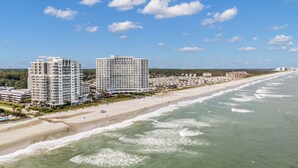 A coastal hotel with multiple high-rise buildings, beachfront access, and a sandy beach.