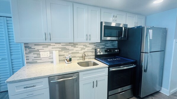 A modern kitchen with white cabinets, stainless steel appliances, and a tiled backsplash.