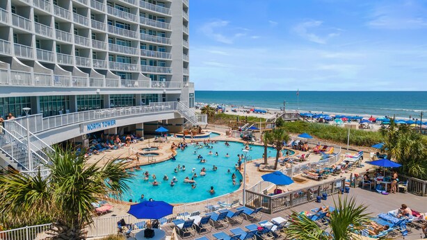 A hotel with a large pool area, a beach, and a North Tower sign.
