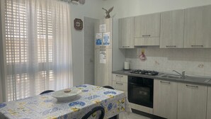Een keuken met een tafel, kastjes, een spoelbak en een fornuis.