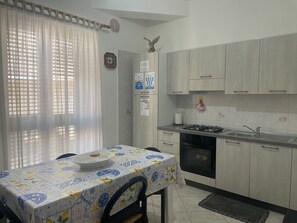 Une cuisine équipée d’une table, de placards, d’un évier et d’une cuisinière.