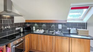 A modern kitchen with dark tiles, wooden cabinets, and a skylight. - Lauras Loft - UK49740 (Greetham, near Horncastle)