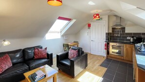 A compact living space with a sofa, a coffee table, a dining area, and a kitchen. - Lauras Loft - UK49740 (Greetham, near Horncastle)