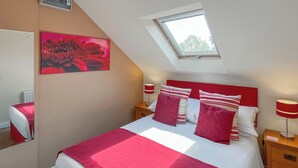 A bedroom with a bed, a skylight, a red and white striped pillow, a red and white bedside table, and a red and white lamp. - Lauras Loft - UK49740 (Greetham, near Horncastle)
