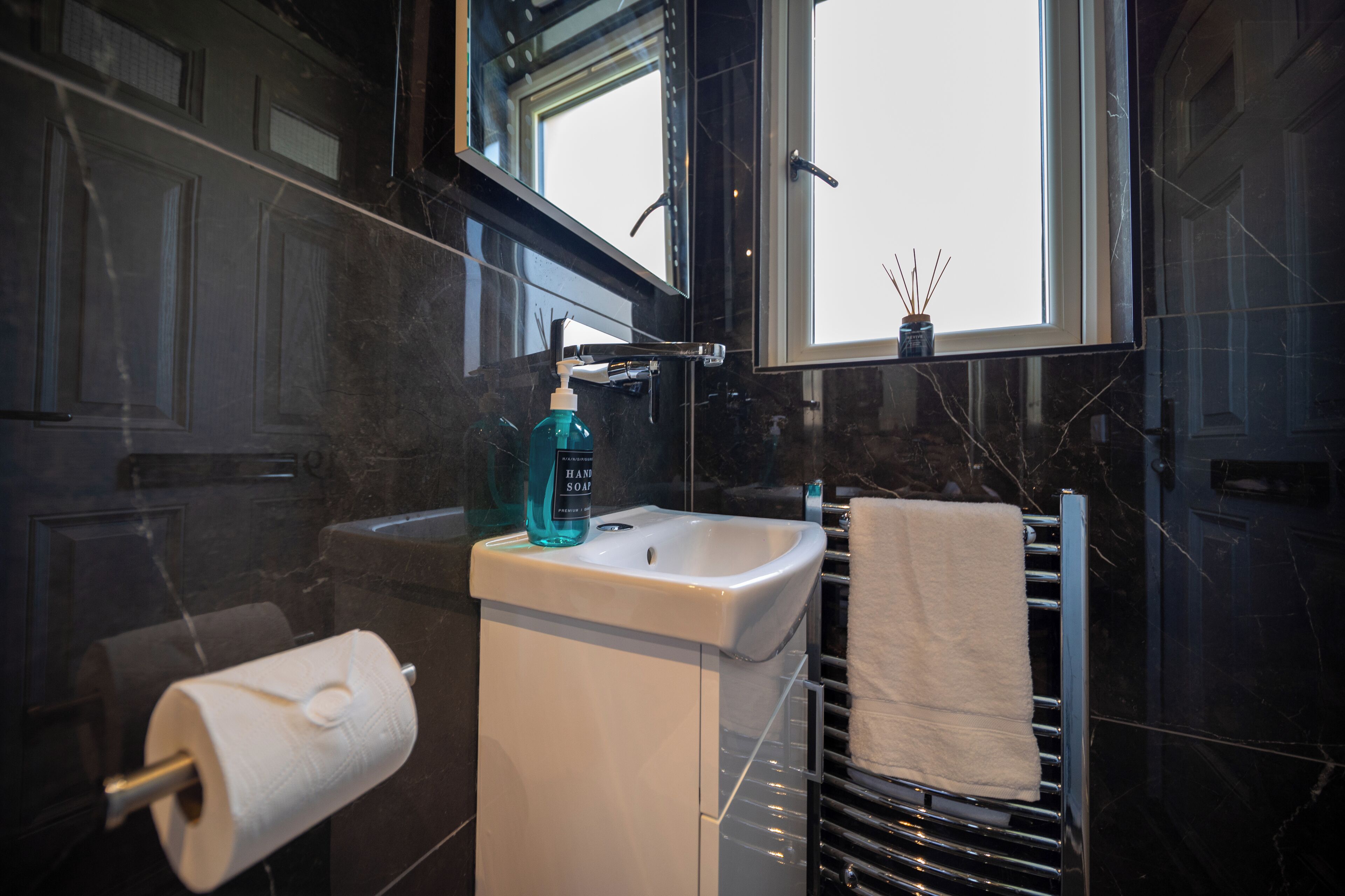 Ein Badezimmer mit einem weißen Waschbecken, einem Handtuchhalter und einem Fenster.