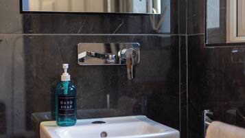 A bathroom with a white sink, a mirror above it, and a bottle of hand soap on the sink.