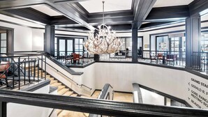 A grand staircase with a modern chandelier, leading to a spacious area with seating and a view of the city. - Hyatt Residence 2052 - 2 Bedroom Residence (Beaver Creek)