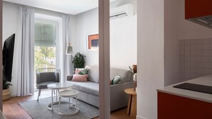 Ein modernes Wohnzimmer mit einem grauen Sofa, einem kleinen runden Tisch und einem Fernseher.