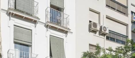 A multi-story building with balconies, air conditioning units, and a gated entrance.