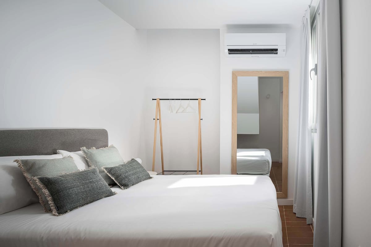 Ein ordentlich eingerichtetes Schlafzimmer mit einem Bett, einem Kleiderschrank und einer Klimaanlage.