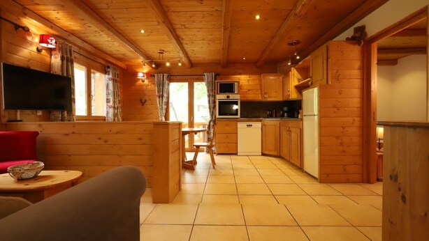 A wooden cabin interior with a living area, kitchen, and dining space.