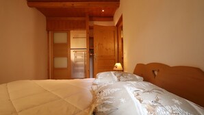 A bedroom with a bed, a nightstand, a wooden headboard, and a door leading to a bathroom.
