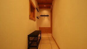 A narrow hallway with a bench, wooden wall paneling, and a hanging coat rack.