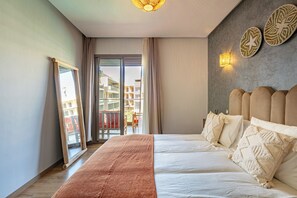 Relax in a spacious room with a large bed, sliding glass door to a balcony, and modern decor.