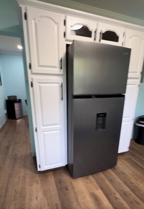 A kitchen with white cabinetry, a stainless steel refrigerator, and a trash can. - Charming 2-bedroom house with WiFi, AC in delightful Christ Church (Christ Church)