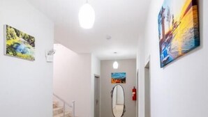 A hallway with a staircase leading to a room, white walls, and a ceiling light.