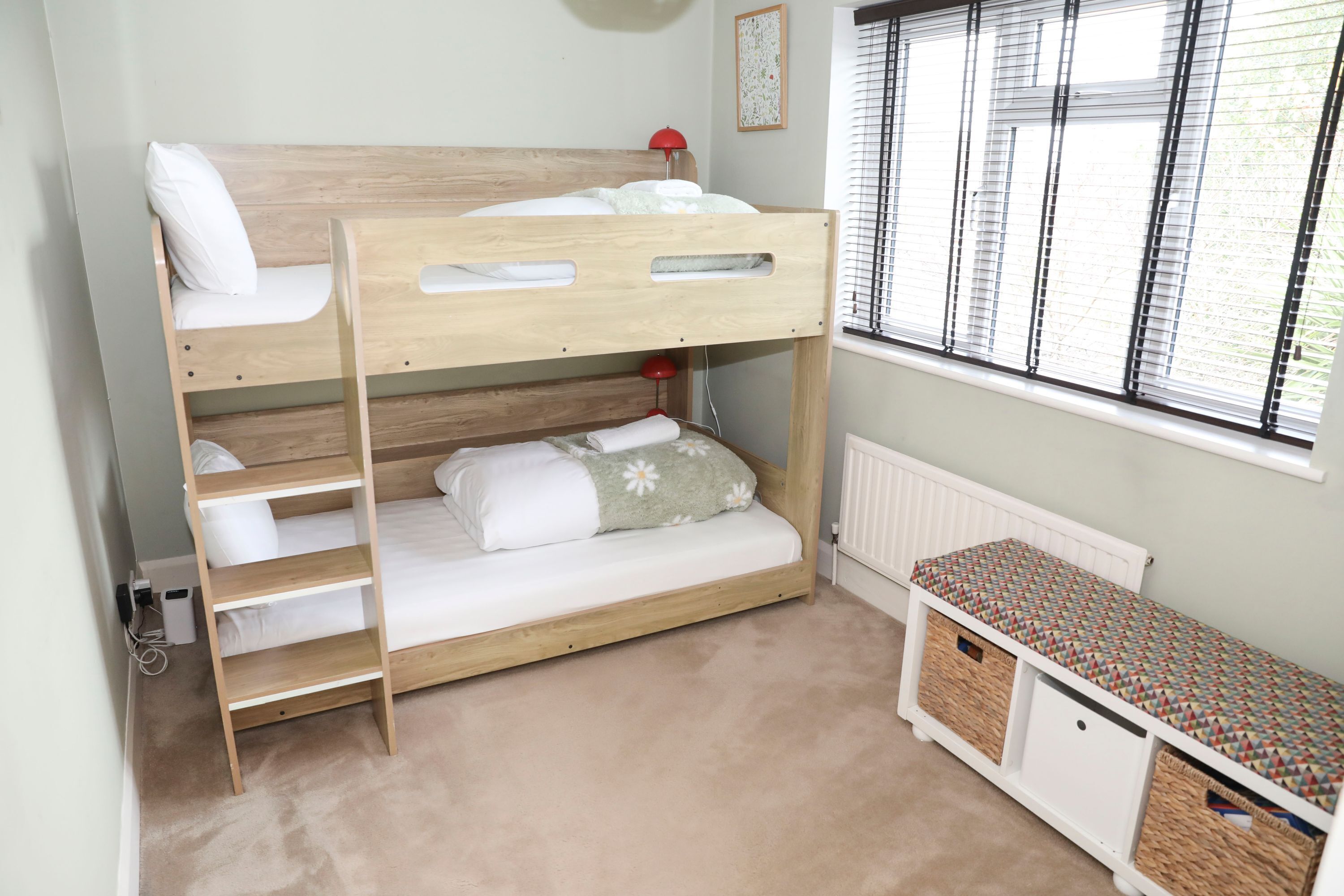 A bunk bed room with a window, a desk, and storage bins.
