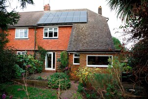 Une maison à deux étages avec une façade en briques, un toit en tuiles et des panneaux solaires sur le toit.