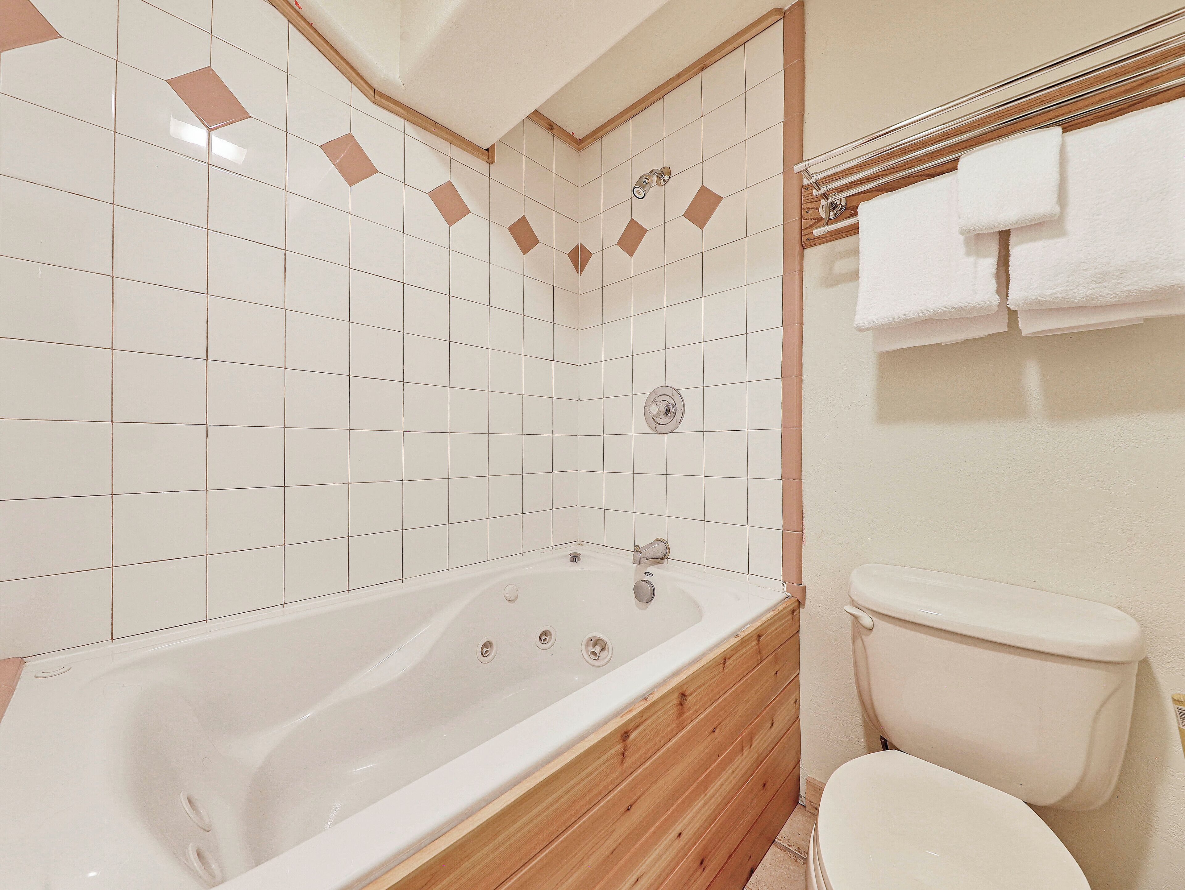 Une salle de bain avec une baignoire, des toilettes et des murs carrelés.