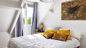 A bedroom with a bed, pillows, a nightstand, a lamp, and a wall art piece.