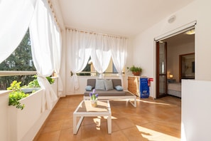 A balcony with a sofa, a small table with a plant, and a view of the outside. - Apartment "Quiet Home' with Private Terrace, Wi-Fi and Air Conditioning (Pula)