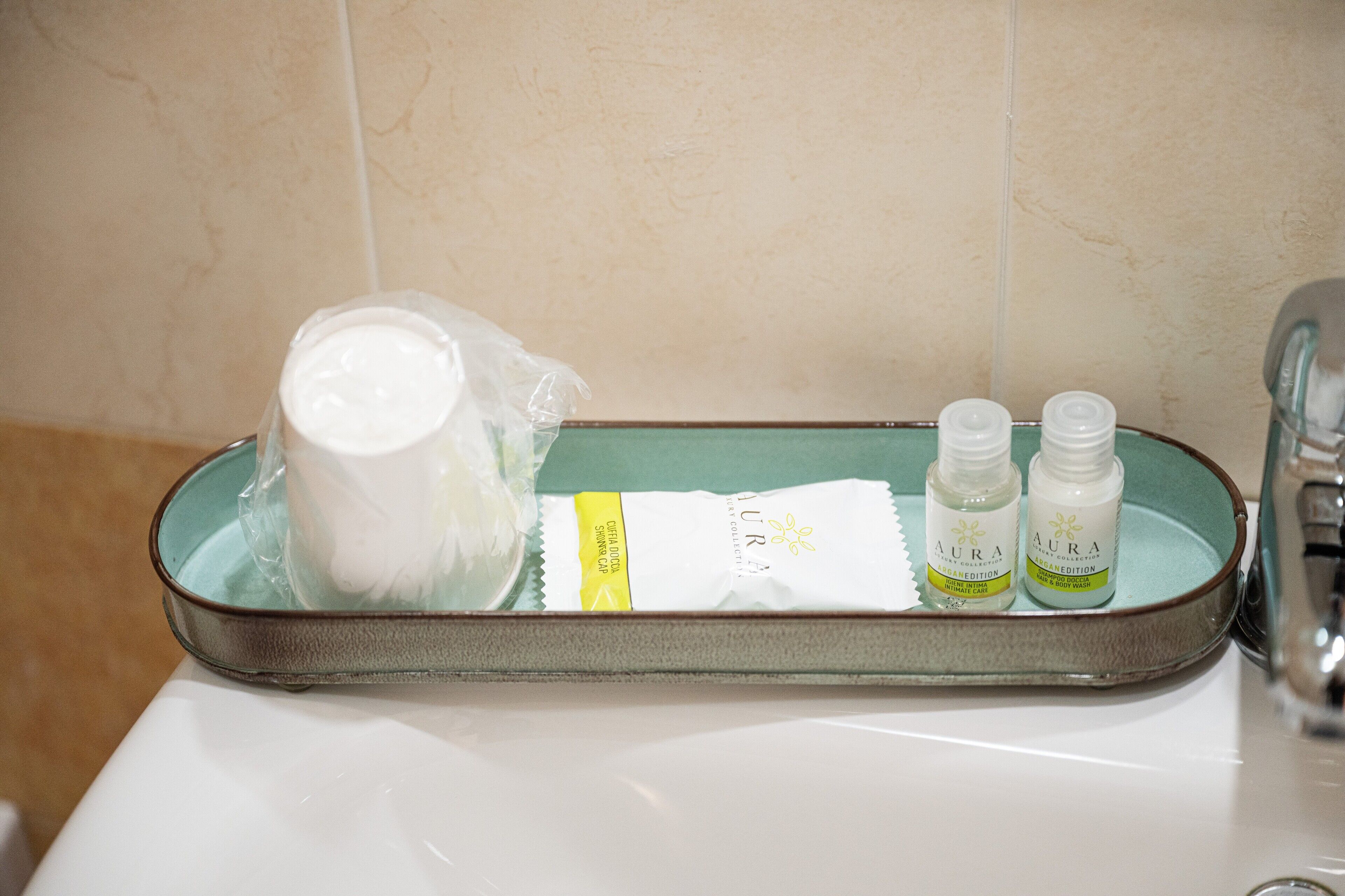A bathroom sink with a tray containing a white bottle, two smaller bottles, and a white package.