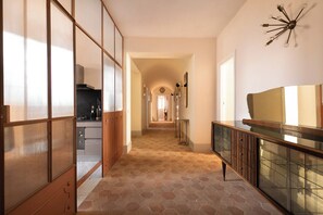 A hallway with a tiled floor, wooden cabinets, and a glass cabinet.