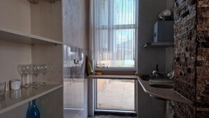A modern kitchen with a marble countertop, a built-in oven, and a window with sheer curtains. - 3-bedroom apartment in Batumi (Batumi)
