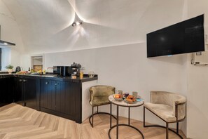 A modern kitchen with dark cabinets, a central island, and a flat-screen TV mounted on the wall. - Boutique Apartment Casa Del Barone (Ventimiglia)
