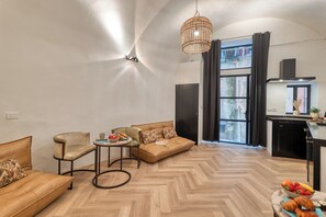 A modern living room with a sofa, armchair, and a small table with fruits and a croissant. - Boutique Apartment Casa Del Barone (Ventimiglia)