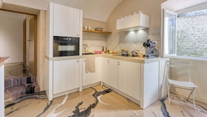 A modern kitchen with white cabinets, a built-in oven, and a stone backsplash. - Boutique Apartment Casa Del Nobile (Ventimiglia)