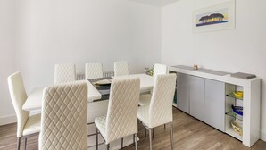 A modern dining area with a white table and chairs, a kitchen counter with shelves, and a framed picture on the wall. - Castle Park is a fantastic gem of a property located in Paignton. (Paignton)