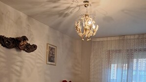 Ein Schlafzimmer mit einem hölzernen Bett, einer Chandelierleuchtre, einem Stuhl und einem Schreibtisch mit einer Lampe.