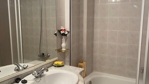 Ein Badezimmer mit Waschbecken, Spiegel, Dusche und Badewanne.