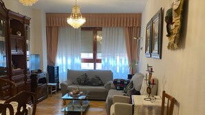 Ein Wohnzimmer mit einer Chandelier, einem Sofa, einem Esstisch mit Stühlen und einem Bücherregal.