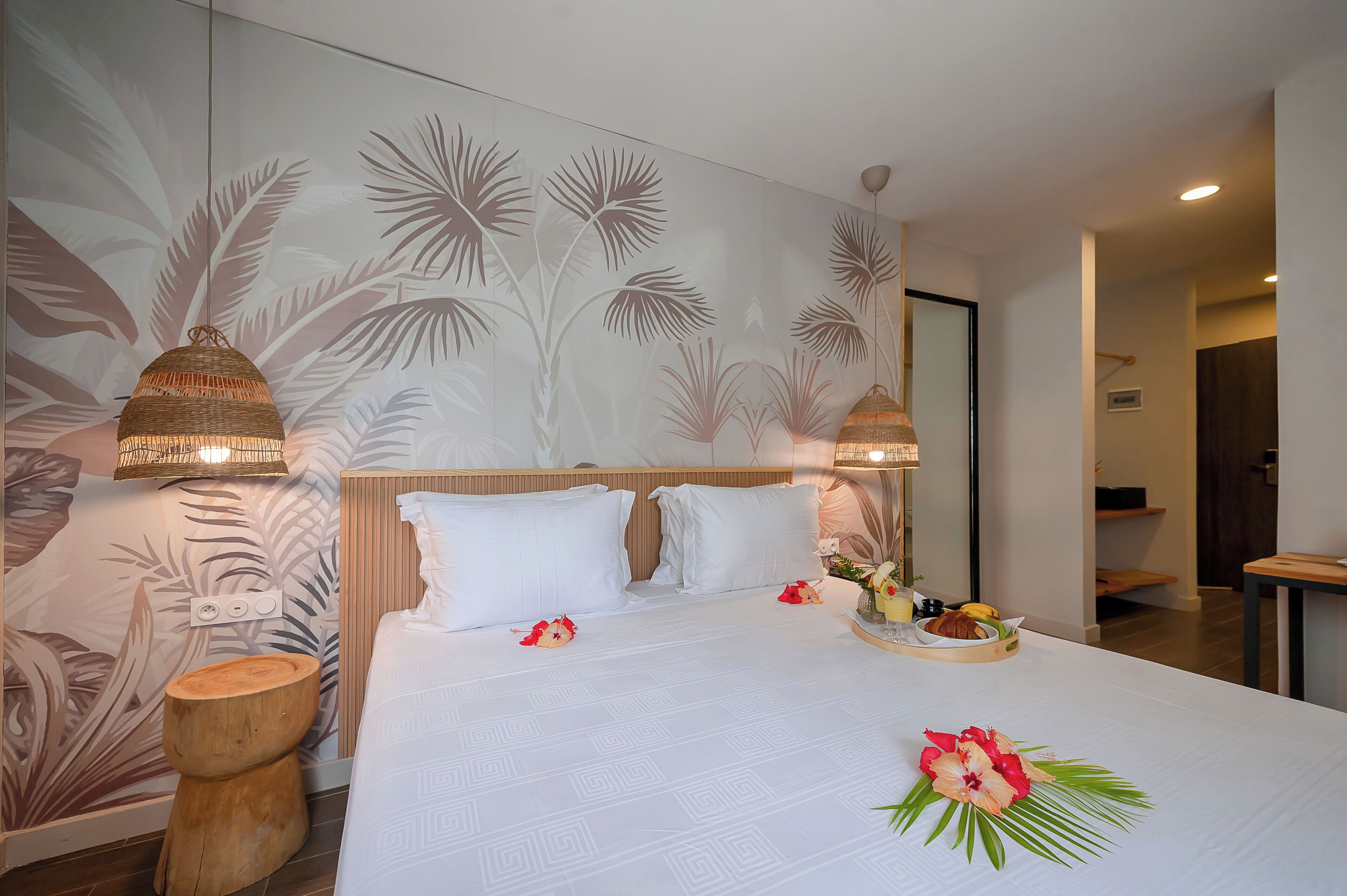 A hotel room with a large bed, two bedside lamps, a wooden stool, and a breakfast tray on the bed.