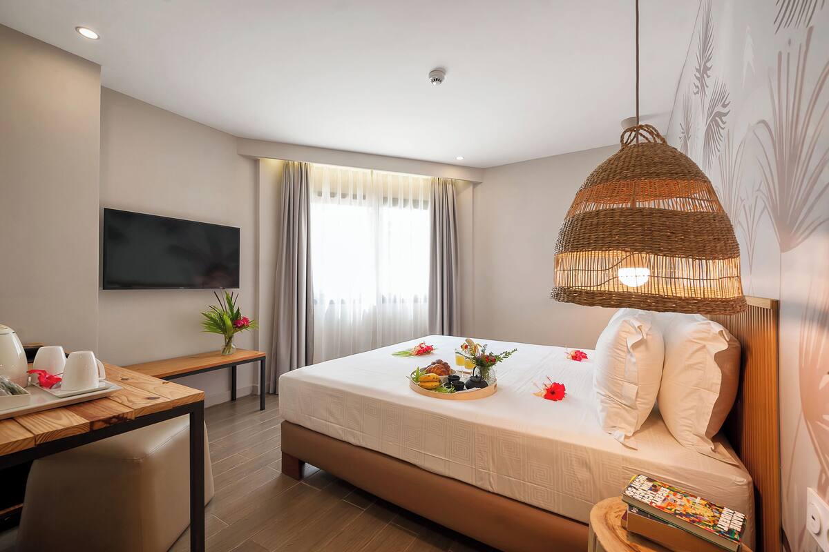 Ein Hotelzimmer mit Bett, Nachttisch, Fernseher und Essecke.