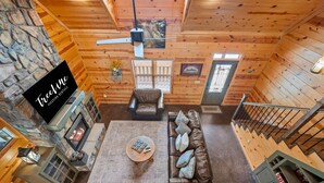 Ein gemütliches Blockhaus-Interieur mit Steinwand, Holzdielen, Kamin, Ledersofa und Essbereich.
