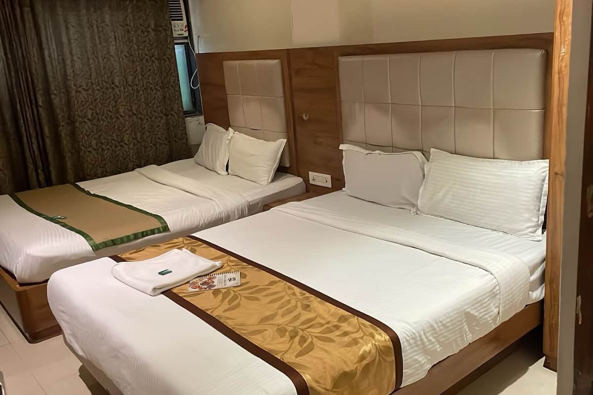 Habitación de hotel con dos camas, cada una con ropa blanca y cabeceros marrones. Un corredor decorativo marrón adorna la cama en primer plano.