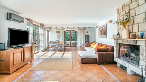Amplia sala de estar con televisor de pantalla plana, chimenea de piedra y comedor con mesa y sillas.