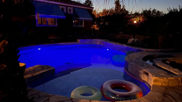 A swimming pool with a stone border, surrounded by a house and vegetation. - Holiday Home 'Beniarbeig' with Mountain View, Wi-Fi and Air Conditioning (El Campello)