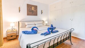 A hotel room with a bed, a wardrobe, a painting on the wall, and a small table with a lamp. - Holiday Home 'Beniarbeig' with Mountain View, Wi-Fi and Air Conditioning (El Campello)