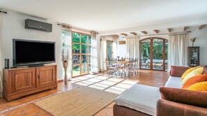 A spacious living area with a television, sofa, and dining table. - Holiday Home 'Beniarbeig' with Mountain View, Wi-Fi and Air Conditioning (El Campello)