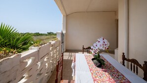 Un balcón con una mesa para dos, barandilla blanca y vista al mar.