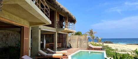 A resort with a pool, lounge chairs, and a beach view.
