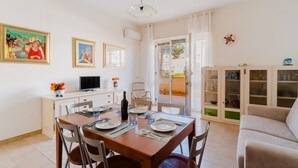Un comedor con una mesa dispuesta para cuatro, sillas, un televisor y obras de arte en las paredes.
